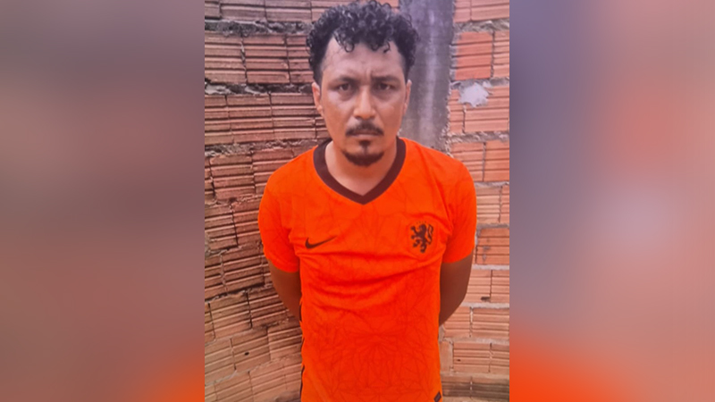 Homem de pele parda com cabelo cacheado vestindo camisa laranja da seleção da Holanda de frente para uma parede de tijolos.