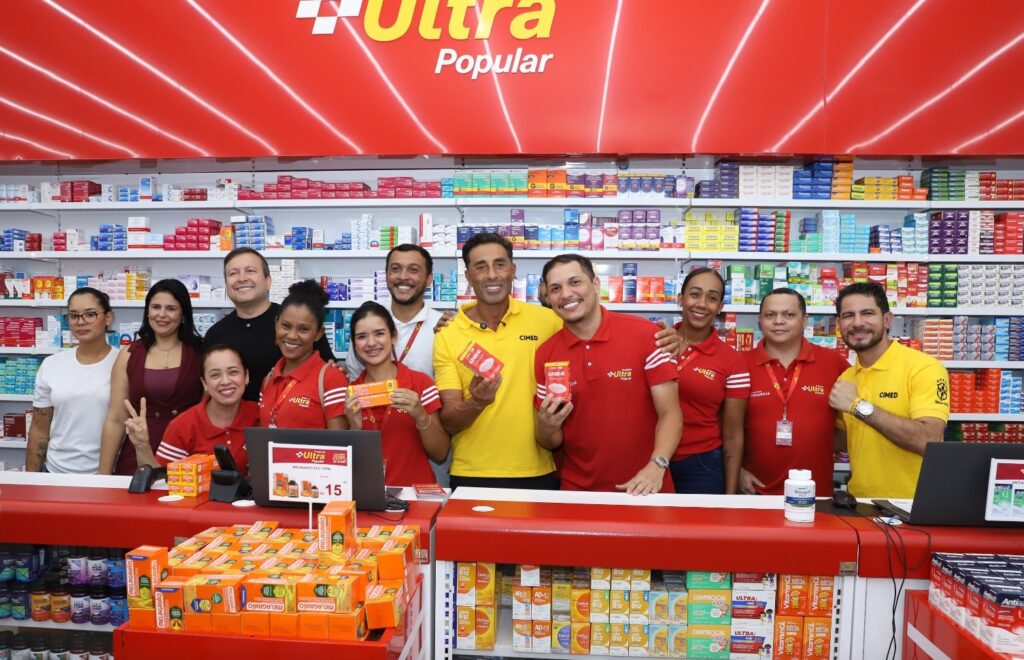 Equipe de funcionários da farmácia Ultra Popular sorrindo atrás do balcão