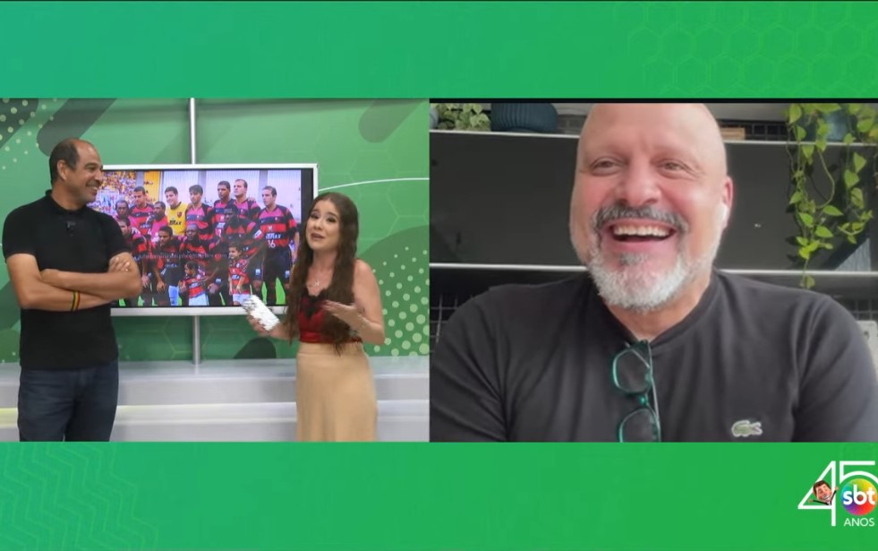 Apresentadora em estúdio de TV comentando foto antiga de um time de futebol ao lado de um homem careca sorridente em vídeo chamada.