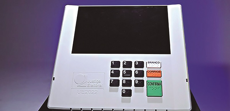 Urna eletrônica modelo UE2022 branca contra um fundo roxo.