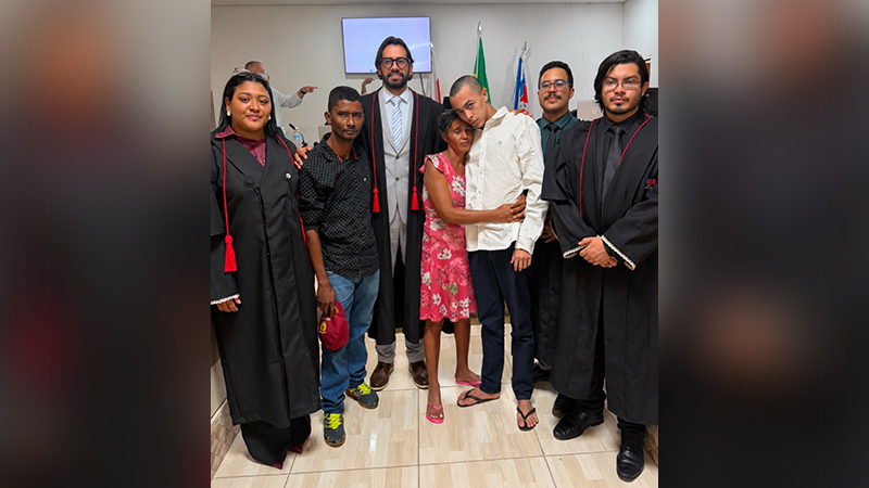 Grupo de pessoas posando para foto em ambiente institucional, incluindo profissionais do direito e cidadãos comuns.