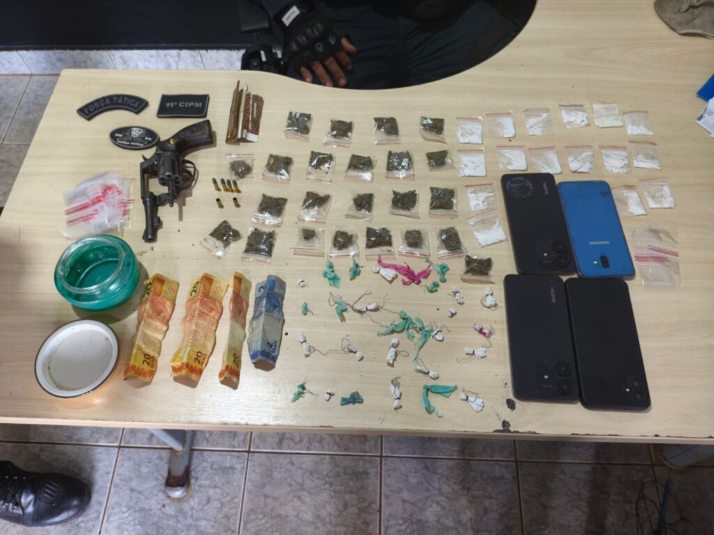Apreensão policial com arma de fogo, drogas embaladas e dinheiro sobre uma mesa.