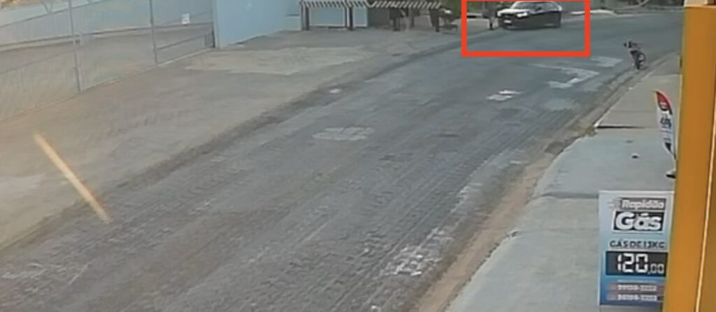 Trecho de rua asfaltada com uma marcação retangular vermelha em um veículo ao fundo