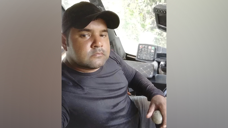 Homem usando boné preto operando cabine de maquinário pesado.