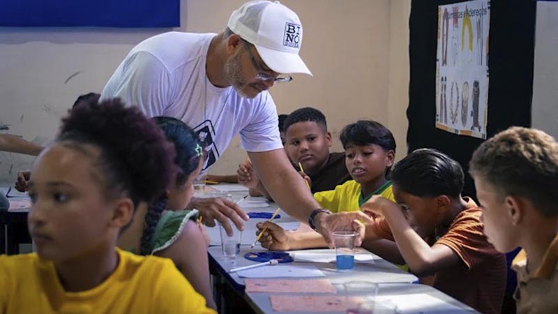 Professor orientando alunos durante uma aula de arte em uma sala de aula