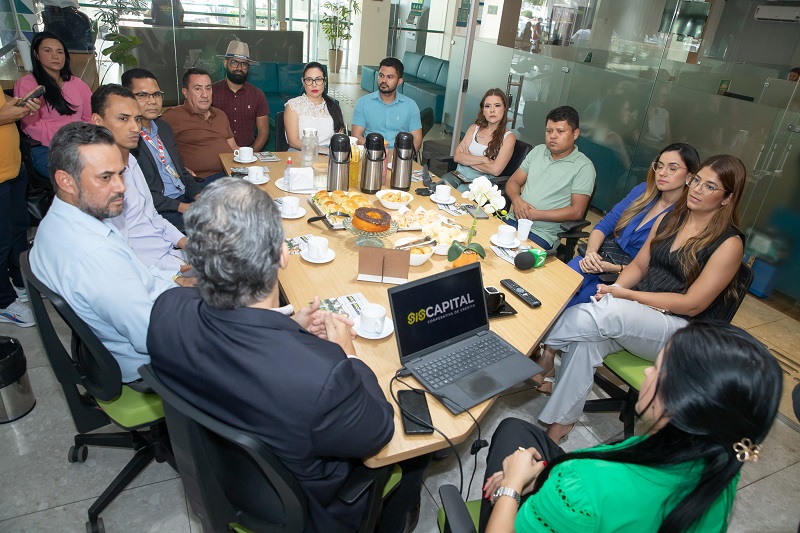Grupo de profissionais em reunião de negócios em torno de uma mesa com café da manhã na sede da Siscapital.