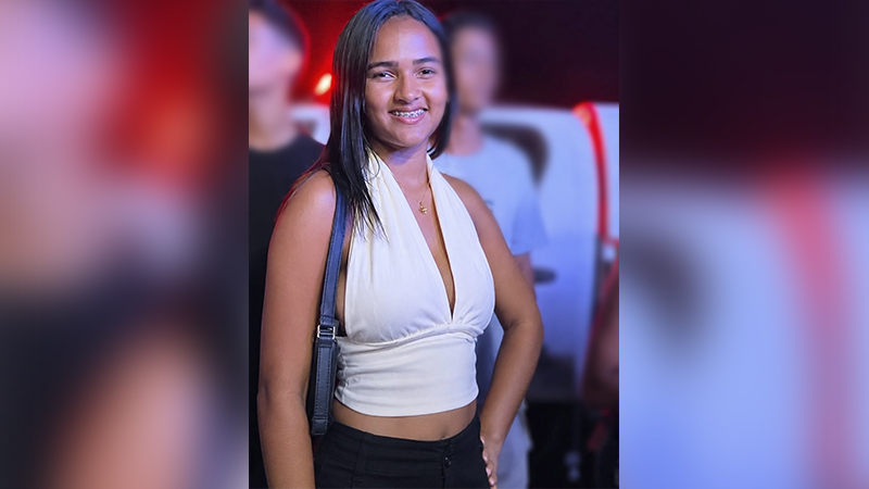 Jovem sorridente vestindo blusa branca sem mangas com aparelho ortodôntico.