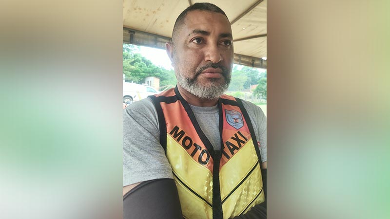Homem de meia-idade com barba grisalha usando colete de mototaxista.
