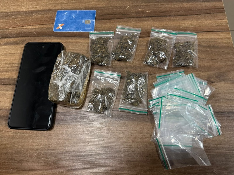 Apreensão policial de substâncias ilícitas embaladas em sacos plásticos, um celular e um cartão de crédito sobre uma mesa.