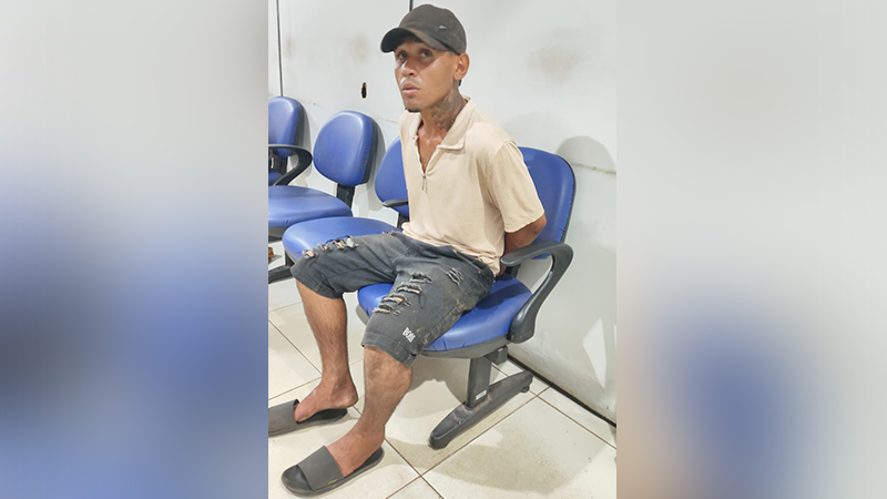 Homem de boné e camiseta bege sentado em cadeira azul.